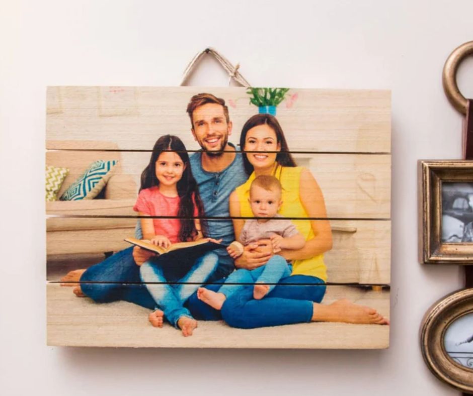 Unique family photo wood plaque hanging on wall showing smiling family of four sitting together indoors