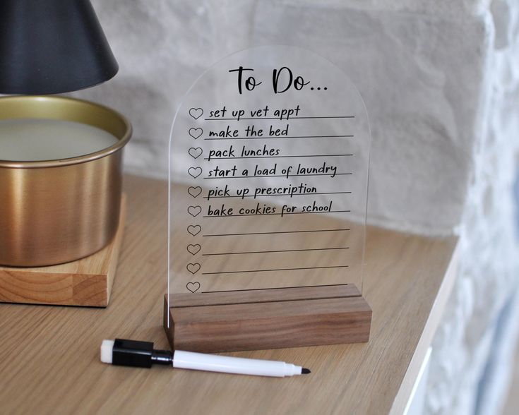 Clear acrylic to do list board with wooden base and black marker on wooden table