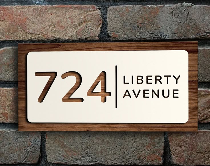 Custom acrylic house name plate with number 724 and Liberty Avenue text mounted on brick wall