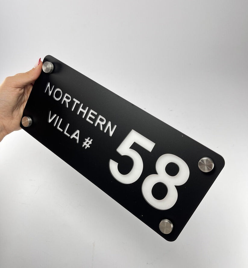 Hand holding custom black acrylic house name plate with Northern Villa 58 text and metal mounts