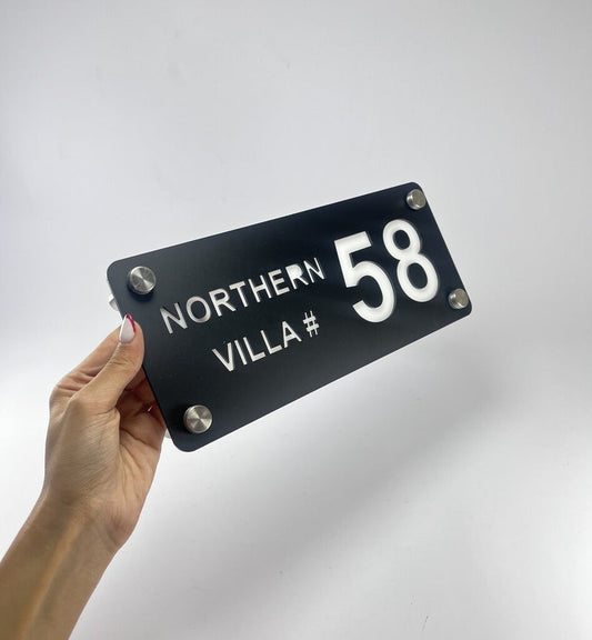 custom black acrylic house name plate with villa number 58 and Northern text held in hand