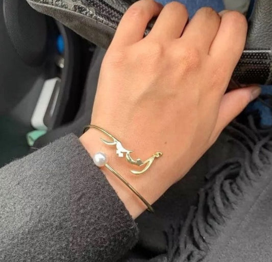 Elegant gold engraved name bangle for women with pearl detail worn on wrist