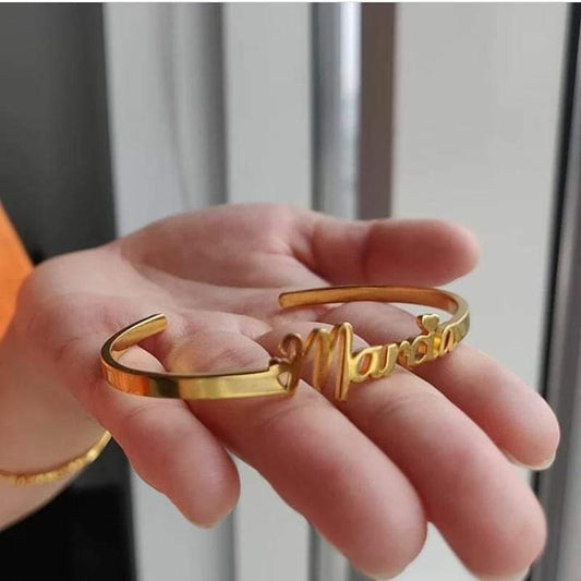 Gold engraved name bangle for women held in hand with personalized name design