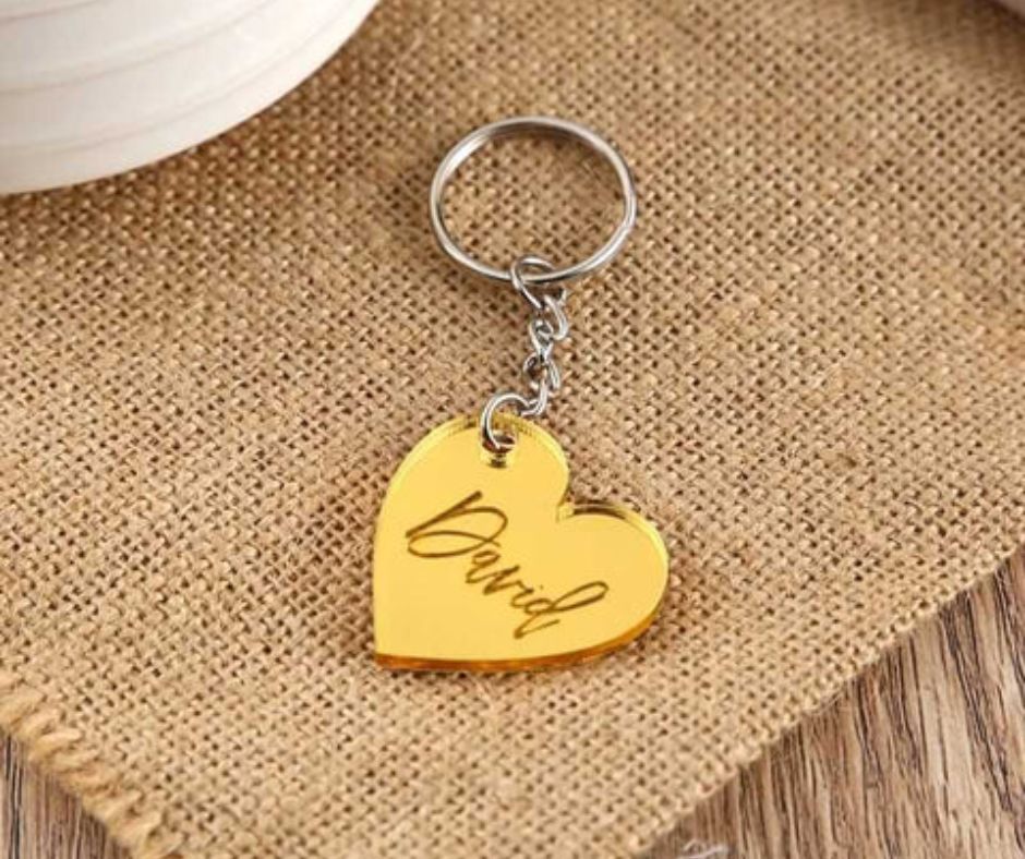 Gold personalized heart keychain with engraved name David on burlap fabric background