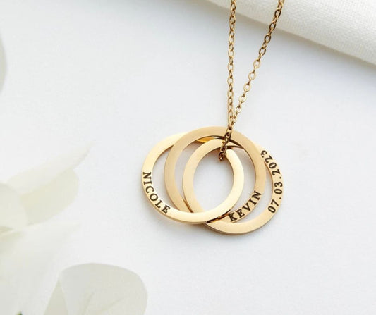 Personalized mom necklace with kids names engraved on three gold rings hanging on a gold chain