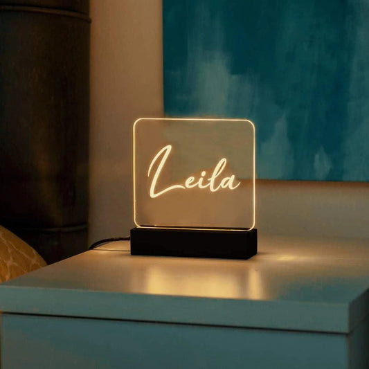 Custom personalized name LED lamp with the name Leila illuminated on a bedside table