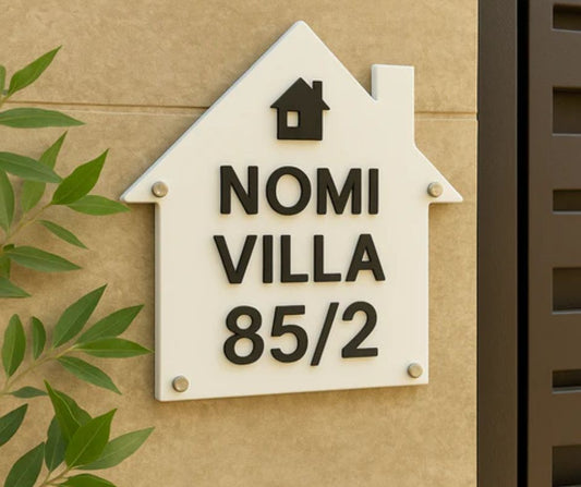 Unique home decor number plate shaped like a house with black text reading Nomi Villa 85 2 mounted on beige wall
